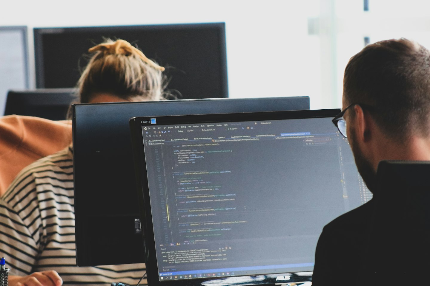 Two engineers working through code at their monitors